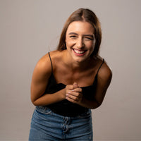 Thumbnail for Smiling woman wearing a black top and jeans, showcasing joy and happiness in a studio setting.