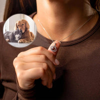 Thumbnail for A person holding the Duo Photo Necklace by Brother & Sisters, showcasing a personalized photo of a dog and cat.