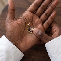 Thumbnail for Thumb warming the gold clover pendant: the hidden photo appears under the thumb while the rest stays black | SKU: TPH-CLVN-GOLD