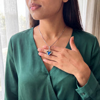 Thumbnail for Woman in an emerald blouse warming the silver clover pendant with her thumb to reveal the photo | SKU: TPH-CLVN-SILVER