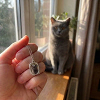 Thumbnail for Customer photo: the silver oval necklace with her cat's photo, her cat in the background | SKU: TPH-OVLN-SILVER